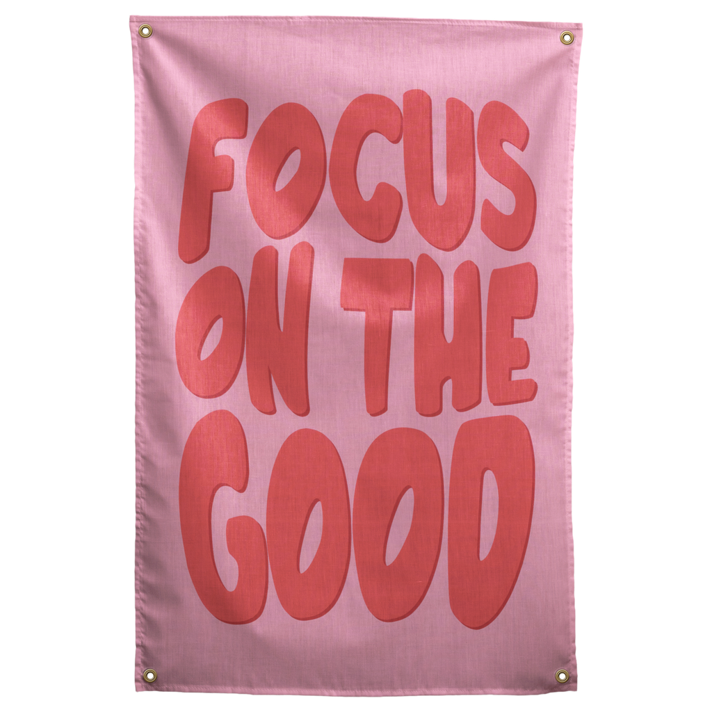 Large rounded coral Focus on the Good lettering fills a pink background on this upbeat Wall Rebel fabric wall flag.