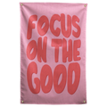 Large rounded coral Focus on the Good lettering fills a pink background on this upbeat Wall Rebel fabric wall flag.