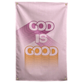 God Is Good lettering trails pastel purple and yellow dimensional shadows across pale pink on this Wall Rebel fabric wall flag.