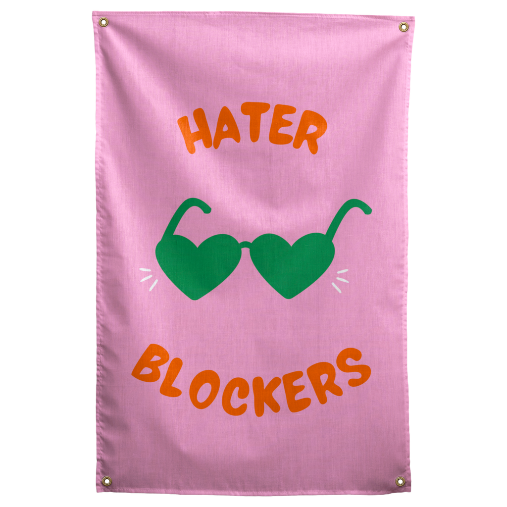 Green heart-shaped sunglasses and orange Hater Blockers lettering stand out on this pink Wall Rebel fabric wall flag.