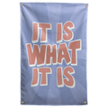Peach It Is What It Is lettering with pale outlines sits over a blue sunburst on this laid-back Wall Rebel fabric wall flag.