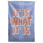Peach It Is What It Is lettering with pale outlines sits over a blue sunburst on this laid-back Wall Rebel fabric wall flag.