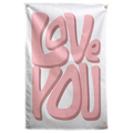 Large soft pink Love You lettering casts darker dimensional shadows on a pale background in this Wall Rebel fabric wall flag.