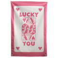 Pink LUCKY YOU lettering, corner hearts and a queen-card illustration sit on cream within a pink border on a Wall Rebel fabric wall flag.