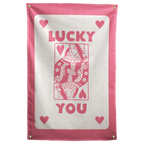 Pink LUCKY YOU lettering, corner hearts and a queen-card illustration sit on cream within a pink border on a Wall Rebel fabric wall flag.