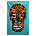 An orange skull with white floral eyes and thick black outlines floats on a turquoise background on a Wall Rebel fabric wall flag.