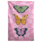 Three green, yellow and pink butterflies stack over a pastel pink checkerboard on this colourful Wall Rebel fabric wall flag.
