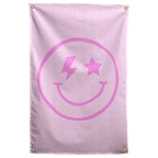A pink smiley with a lightning-bolt eye and a star eye sits on pale pink in this playful Wall Rebel fabric wall flag.