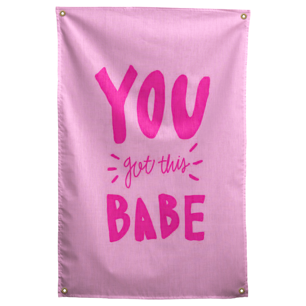 Bright pink You Got This Babe lettering with small accent strokes fills a pale pink Wall Rebel fabric wall flag.